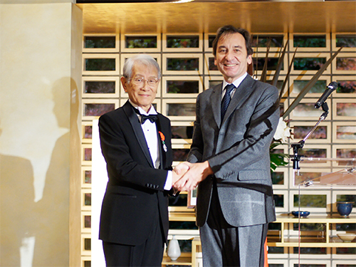 握手をする松本紘理事長（左）とティエリー・ダナ駐日フランス大使（右）の写真