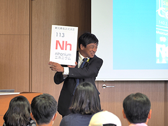写真:「ようこそ、113番元素ニホニウムの生誕地、理研仁科センターへ」講演会中の延與秀人仁科加速器科学研究センター長