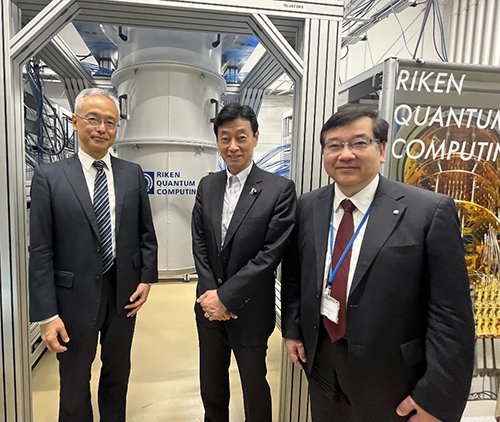 国産超伝導量子コンピュータ初号機の前に立つ西村 大臣、五神 理事長、中村 センター長の写真