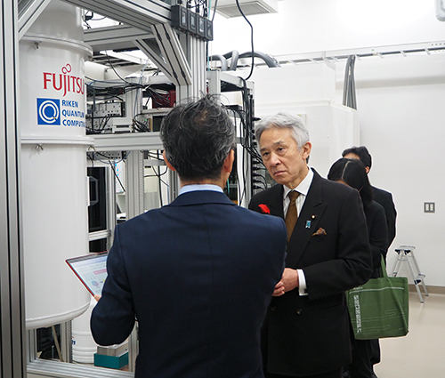 超伝導量子コンピュータの前で説明を受けられる盛山 大臣の写真