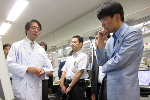 笹井副センター長より再生医療研究について説明を受ける山本大臣の写真