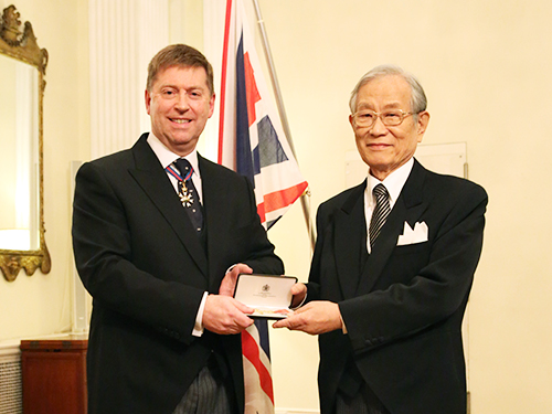 叙勲式の写真:ポール・マデン駐日英国大使より勲章を受け取る松本紘理事長