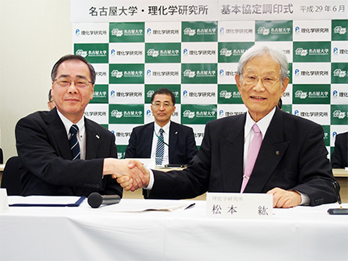 調印後握手を交わす松尾総長（左）と松本理事長（右）の写真