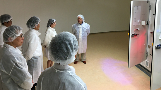次世代栽培システム室で和田チームリーダー（右）から説明を受けられる片山大臣（中央奥）の写真
