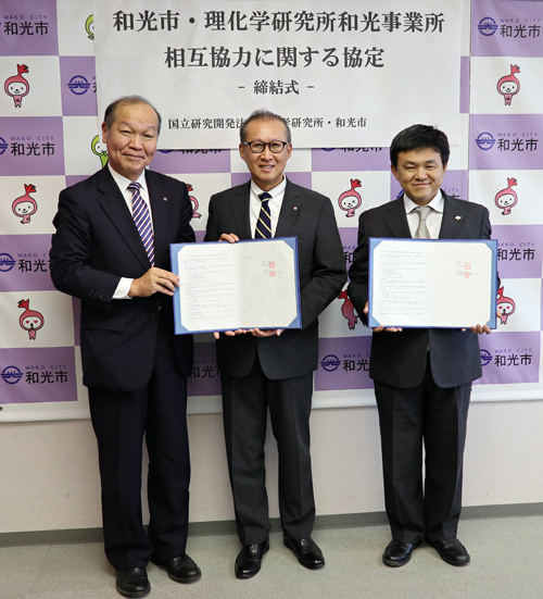 協定書を手にする（左から）船田孝司理研和光事業所長、加藤重治理研理事、松本武洋和光市長の写真