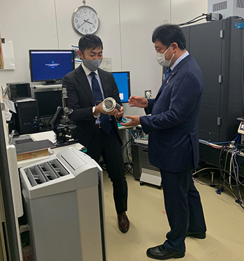 実験室を見学される田中副大臣と村山正宜チームリーダーの写真