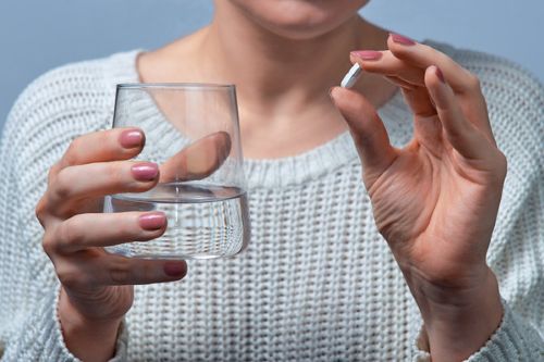 image of a woman holding a pill
